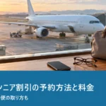 朝の空港の窓から見える旅客機とスマートフォン・老眼鏡を置いたカウンター